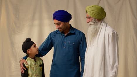 Studio-Shot-Of-Multi-Generation-Male-Sikh-Family-Wearing-Turbans-Standing-Against-Plain-Background